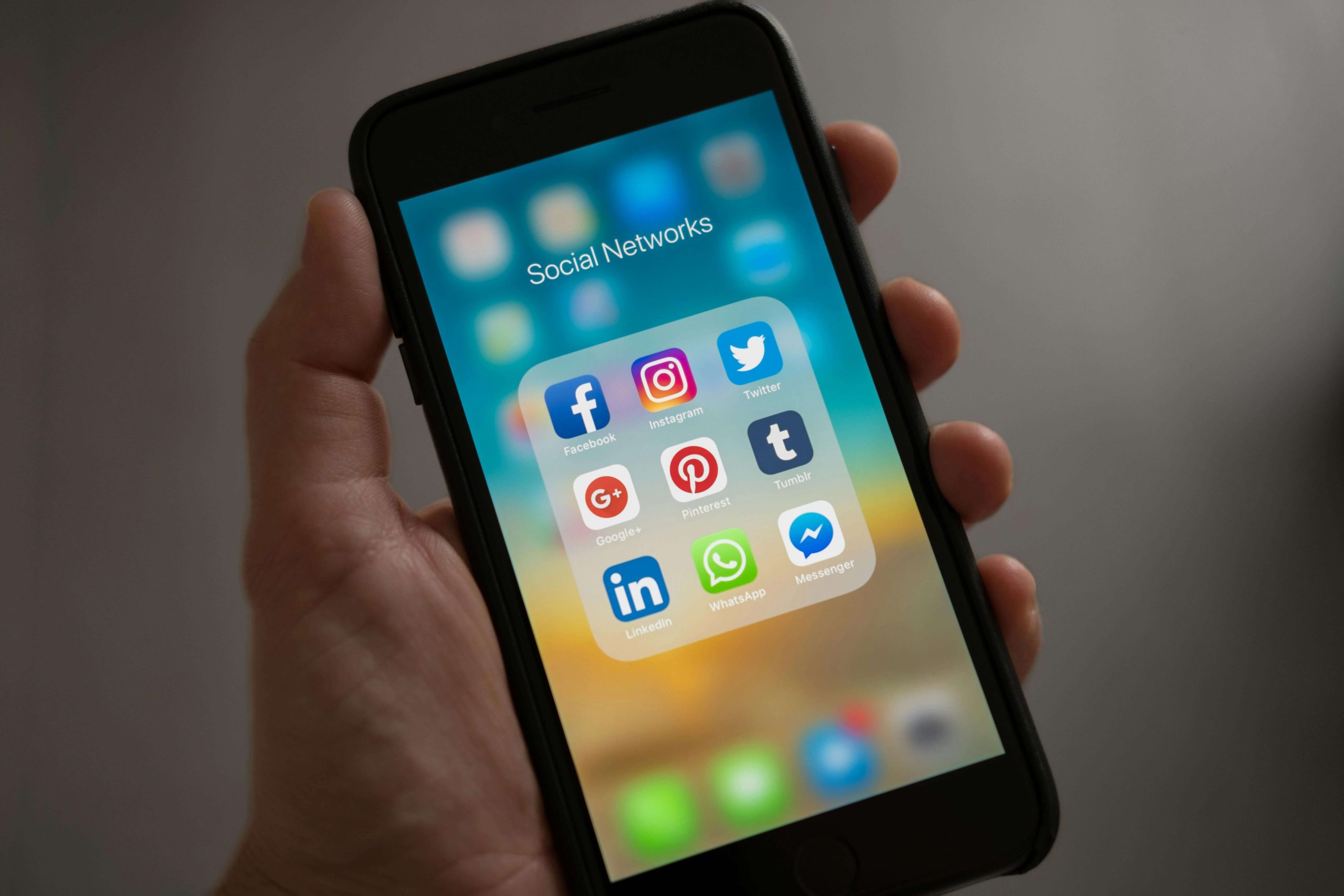 A person holding a phone with their left hand. The phone is opened to an apps folder called "Social Networks", featuring the app logos of Facebook, Instagram, and Pinterest. A person holding a phone with their left hand. The phone is opened to an apps folder called "Social Networks", featuring the app logos of Facebook, Instagram, and Pinterest.