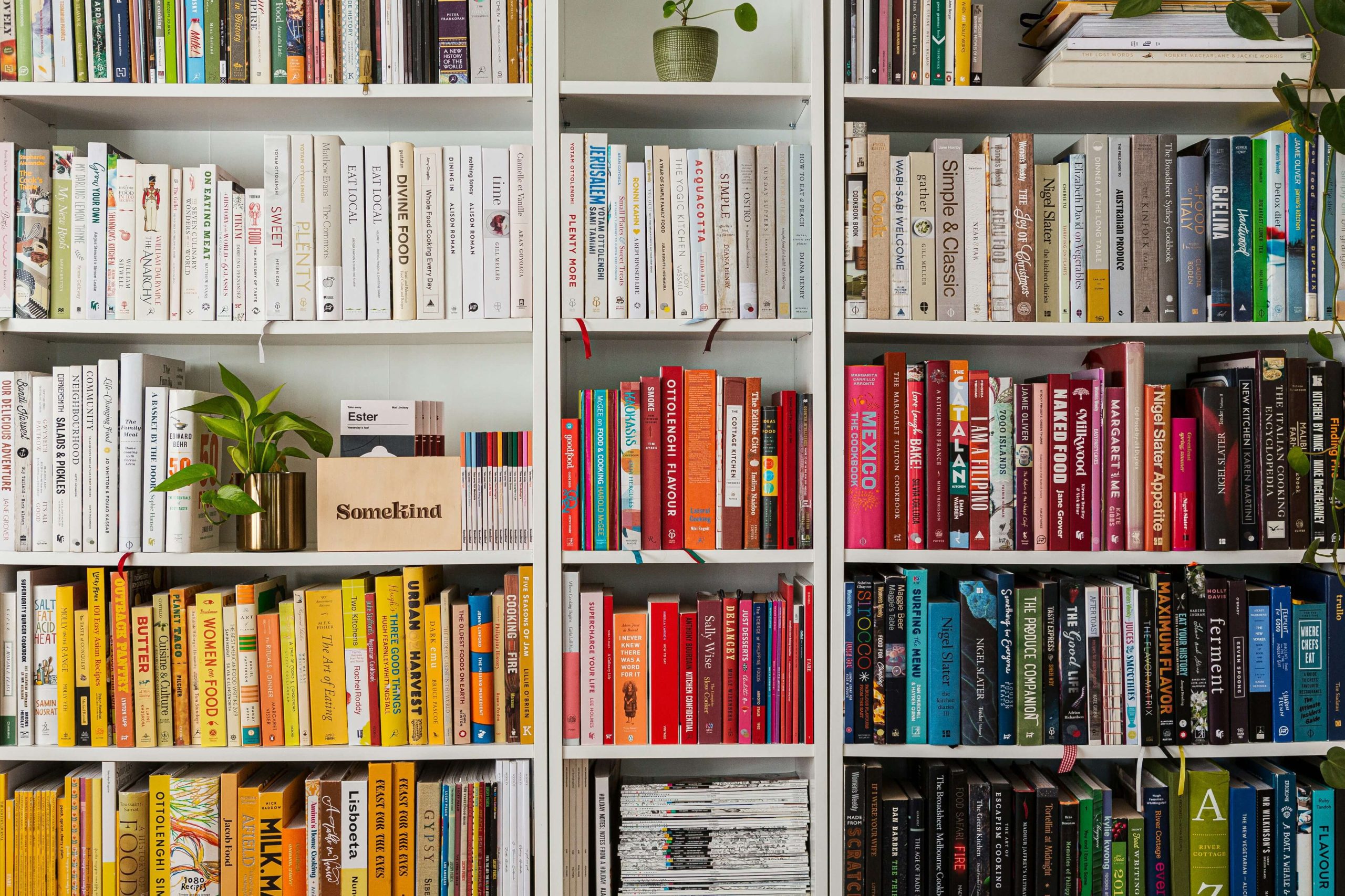 Three white bookshelves filled with multicolored books. Three white bookshelves filled with multicolored books.