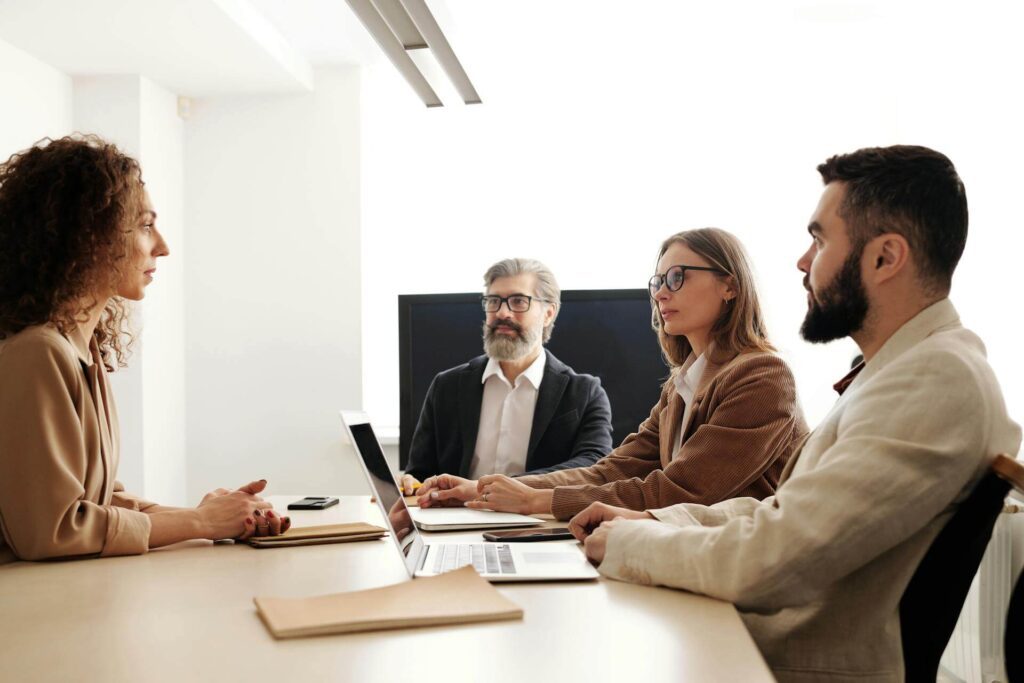 Four people sitting around a table, having a meeting, to show the importance of team management during layoffs.