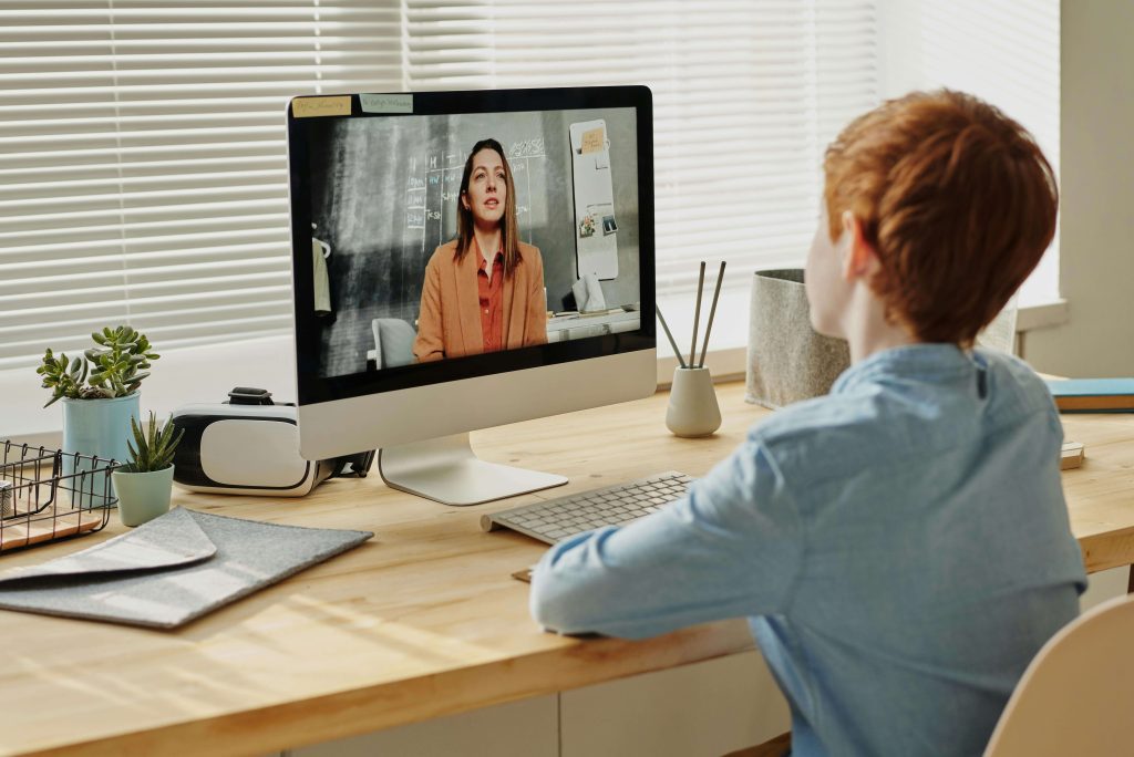 A boy speaking to a teacher via video call.