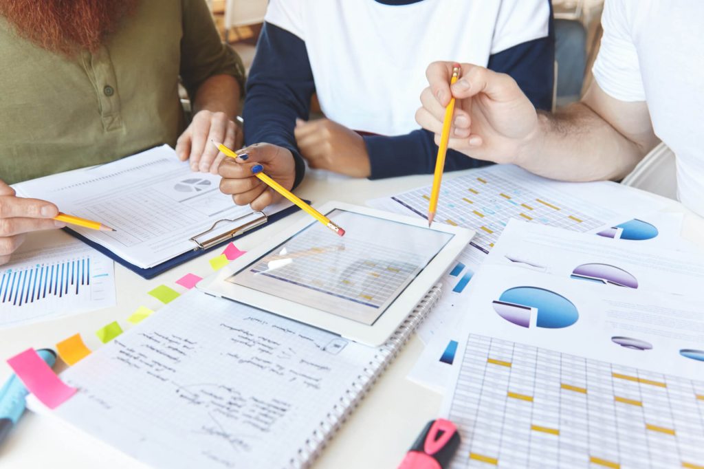 A group of people working together with different data sets laid out on papers in front of them.