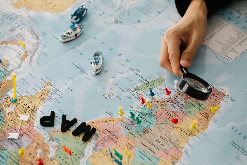 A person holding a magnifying glass over a map of the world.