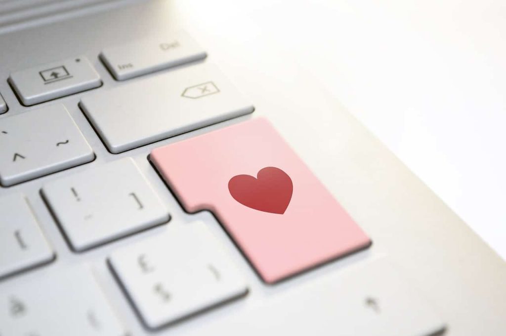 Red heart on a pink enter button on an otherwise white keyboard, symbolically implying making writing / typing personal.