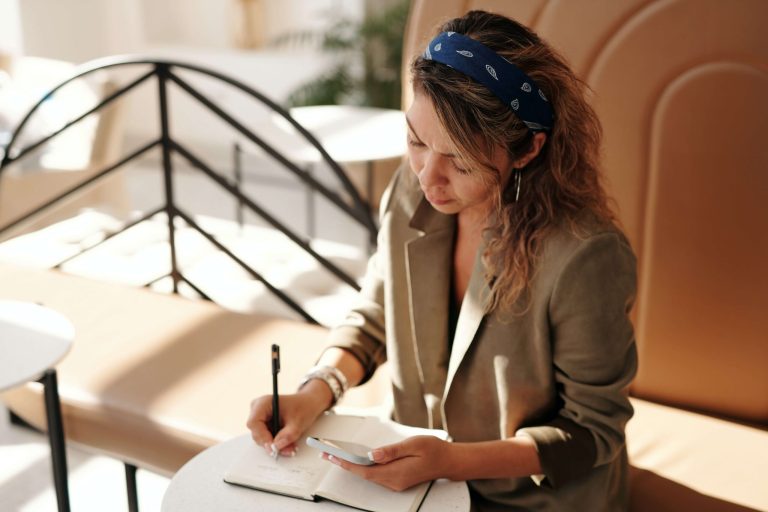 A woman sitting down and writing in a notebook.