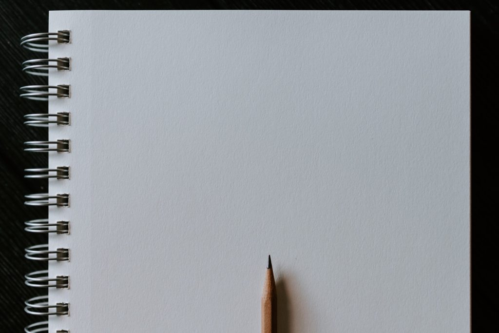 A notepad opened to a blank page with a pencil in the middle.