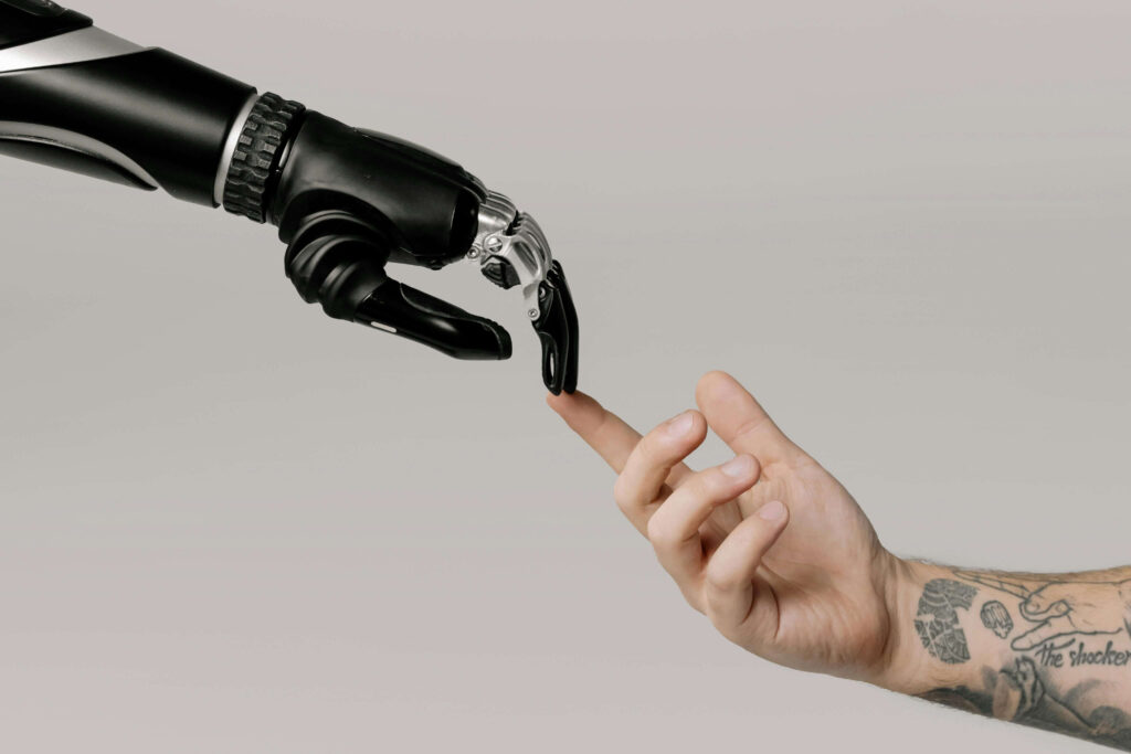 A bionic hand and a human hand pointing and touching each other to symbolise the growing collaboration between AI and work.