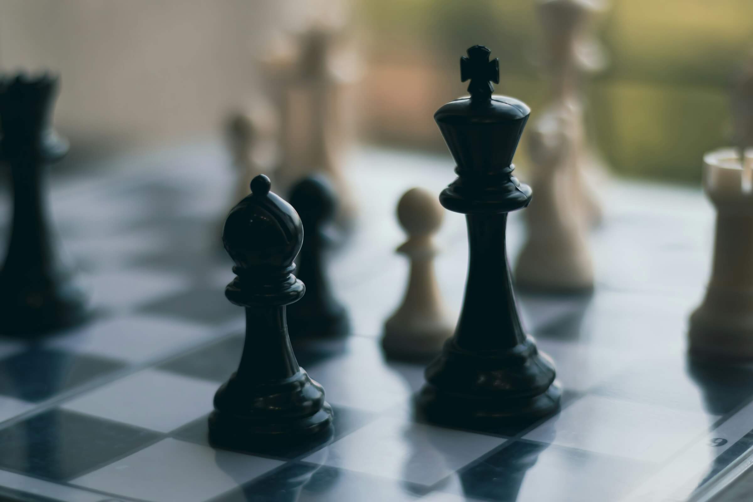 A chess board with the main focus showing a bishop in front of the King to represent how AI can be used in business.