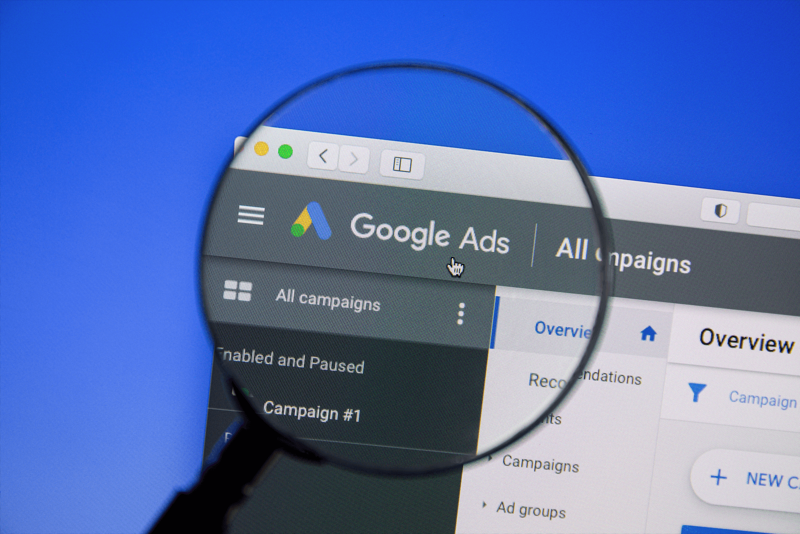 An image of the Google Ads dashboard on a screen and a magnifying glass zooming in the left corner of the dashboard. An image of the Google Ads dashboard on a screen and a magnifying glass zooming in the left corner of the dashboard.