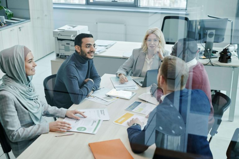 A group of office workers is sitting and talking around a table.