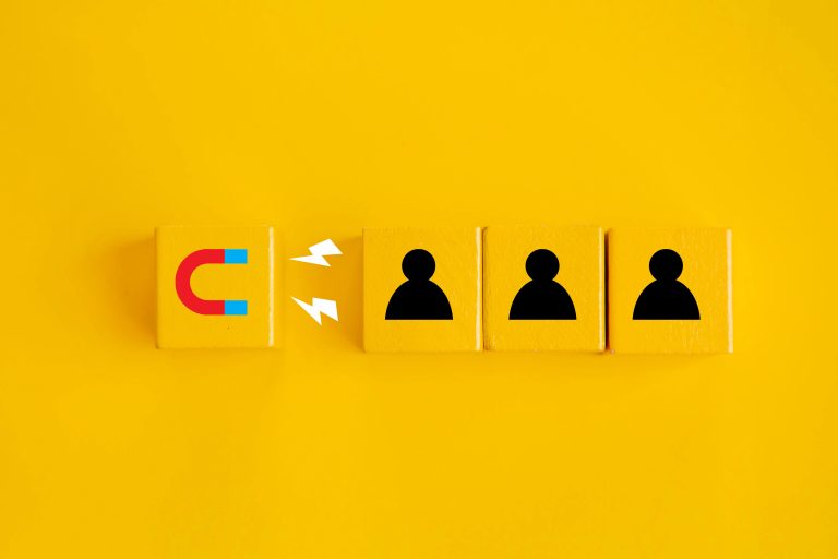 A mustard yellow background showing an icon of a magnet attracting icons of people to denote lead magnets.
