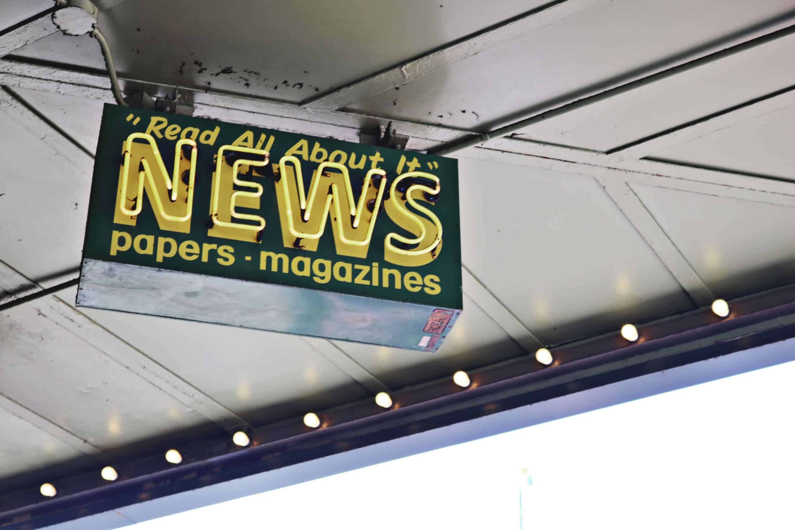 A news inscription on neon signboard, hanging on a street.