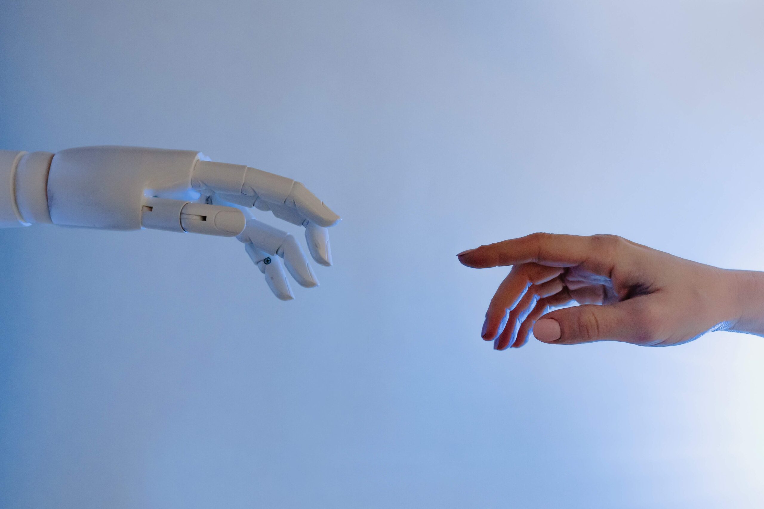 Artificial intelligence robot and a human hand reaching for each other.
